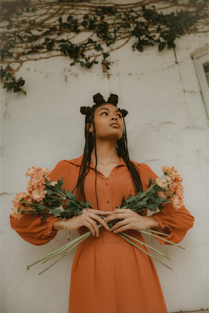 Frau mit Blumen in der Hand und orangem Kleid